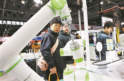 2025上海国际机床展上,参观者在一个进行作业演示的双臂协同机器人前驻足观看。  新华社记者 方喆摄