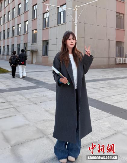 刘沫含在宿舍前拍照，她身着“双十一”花200多元买的风衣。 受访者供图