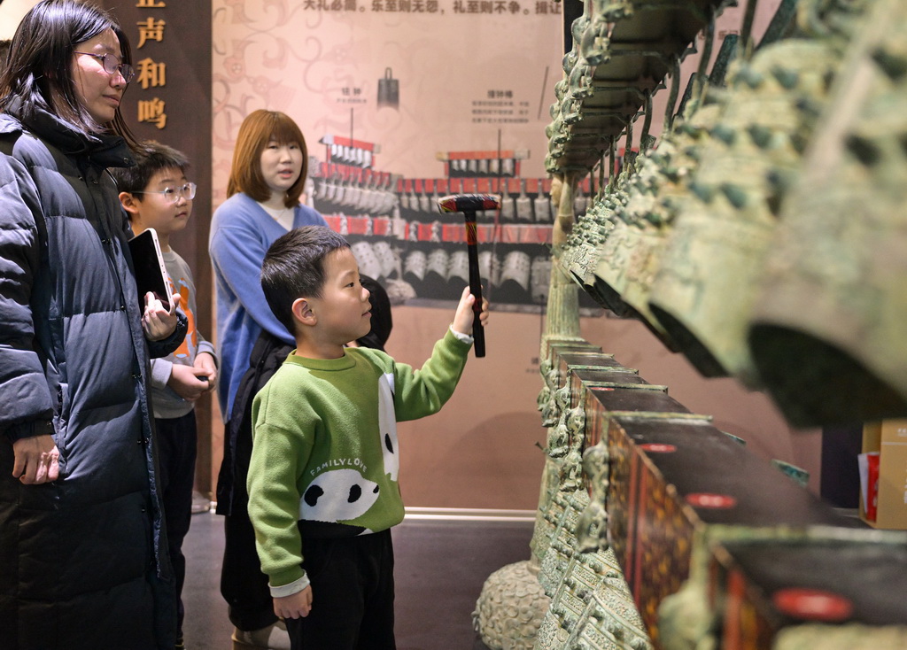 1月3日，小游客在中国考古博物馆互动展区参加仿古编钟的敲击体验活动。