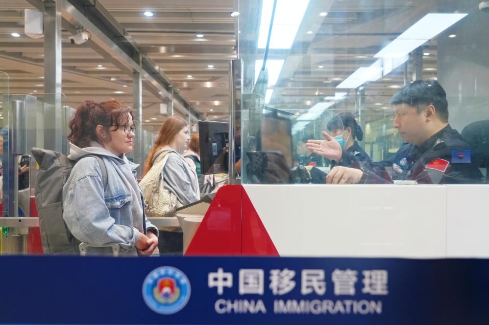 北京边检总站移民管理警察为入境旅客办理边防检查手续。（北京边检总站供图）