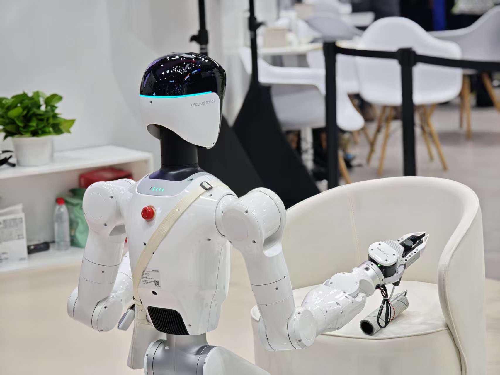人形机器人用卷毛轴清理沙发。人民网记者 黄盛摄