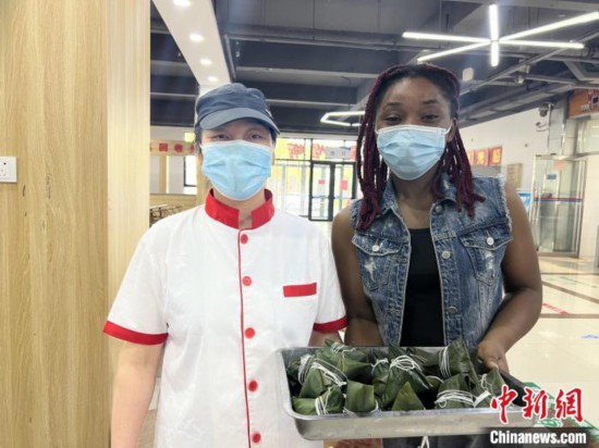 图为尼日利亚留学生(右)手捧包好的粽子。 张婧璇 摄