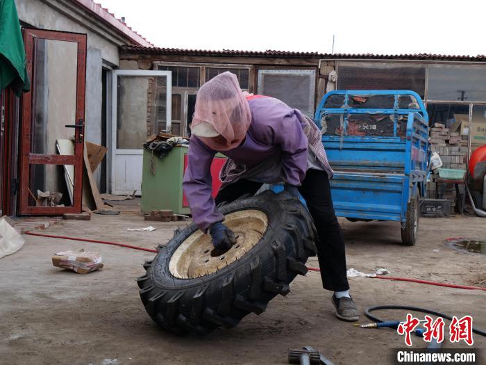 图为张云侠抬起几十斤重的轮胎。　胡建华 摄
