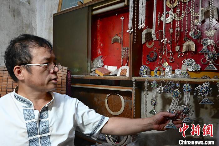 图为吴共能在展示已做好的银饰品。　侯芸莹 摄