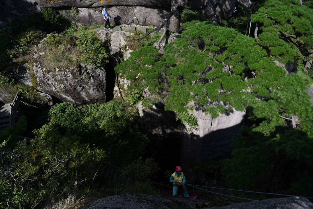 8月15日,李培生(下)在黄山风景区的悬崖峭壁间清捡垃圾,胡晓春(上)在迎客松附近巡查。新华社记者 张端 摄