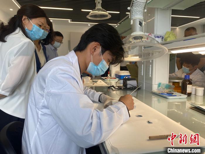 与会人员学习了解文物修复工作。 李明芮 摄 与会人员学习了解文物修复工作。 李明芮 摄