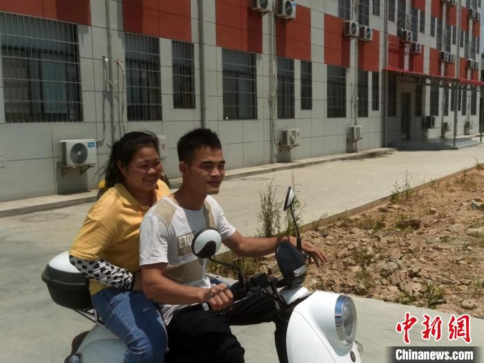 覃雪嫔和丈夫一起骑电动自行车上班。　蒋雪林 摄