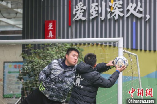 图为球队教练(右1黑色外衣)在手把手指导球队的守门员如何用正确的姿势扑球。　刘力鑫 摄
