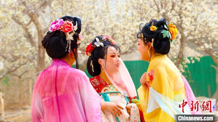 身着古装的群众穿梭于梨园，惬意交谈。　王小军 摄