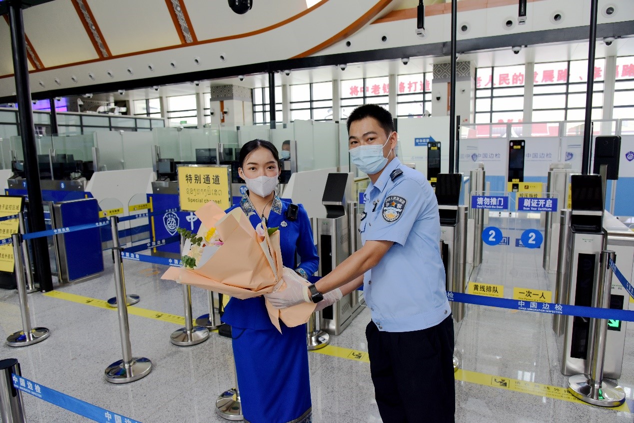 磨憨出入境边防检查站民警为中老铁路第100万名出入境旅客,D888次国际旅客列车老挝籍乘务员森达拉·妮缇娅(Sengdala Nitiya),送上鲜花。黄远飞 摄